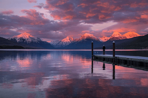 A landscape photo at dawn, there is a distant snow capped mountain range, in the